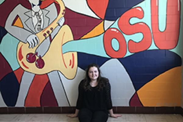 Audrey Watkins poses with her mural in Hughes Hall