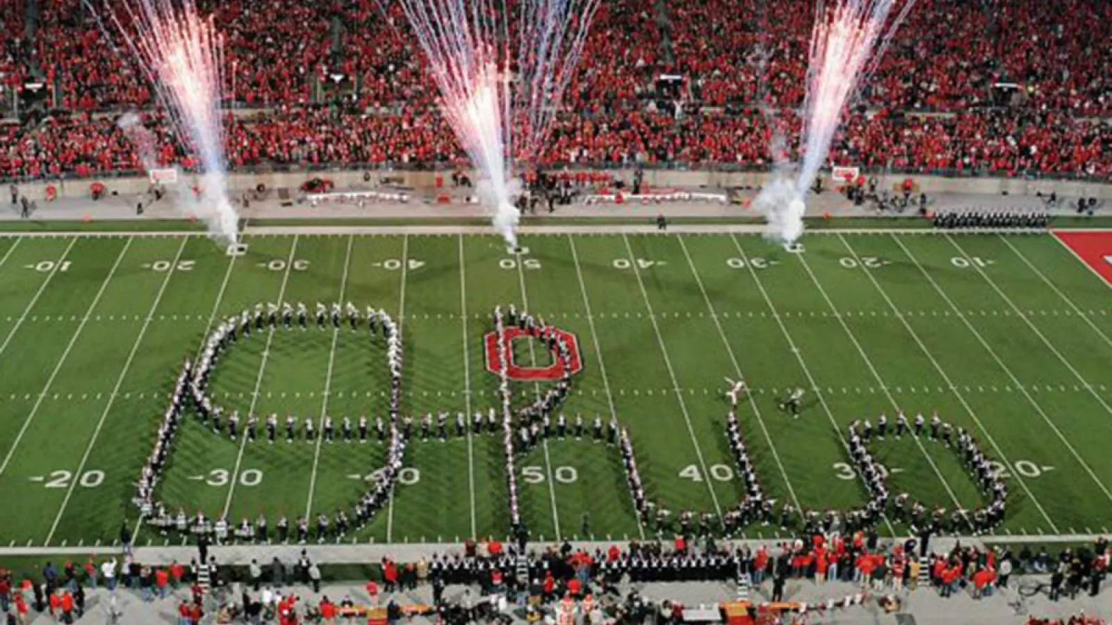 The Ohio State Marching Band forms a Script Ohio with fireworks in the background