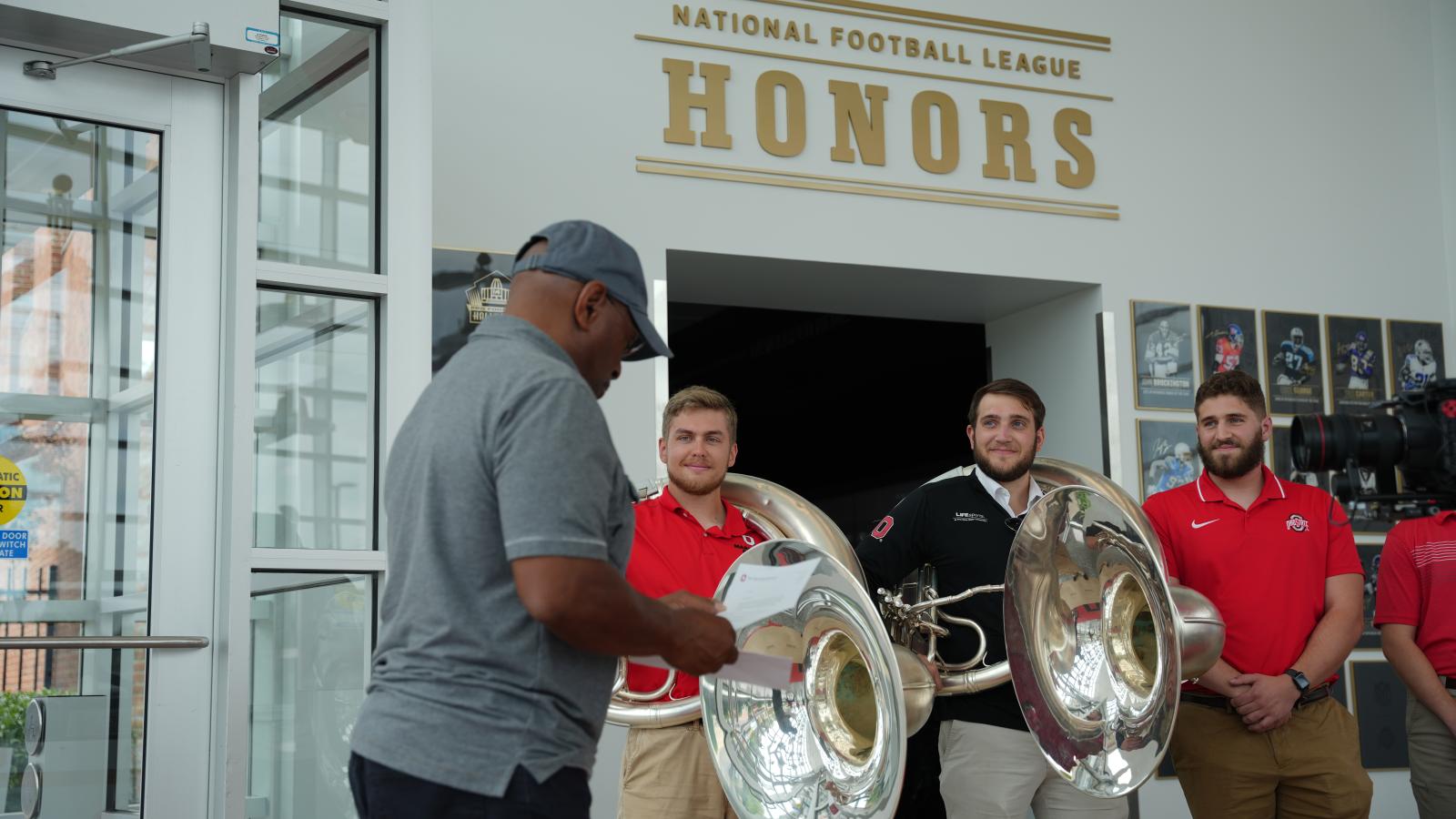 Sousaphone players listening to Archie read to invitation